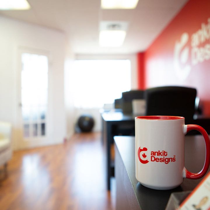 Ankit Designs branded mug sitting on a table inside Ankit Designs office lobby area